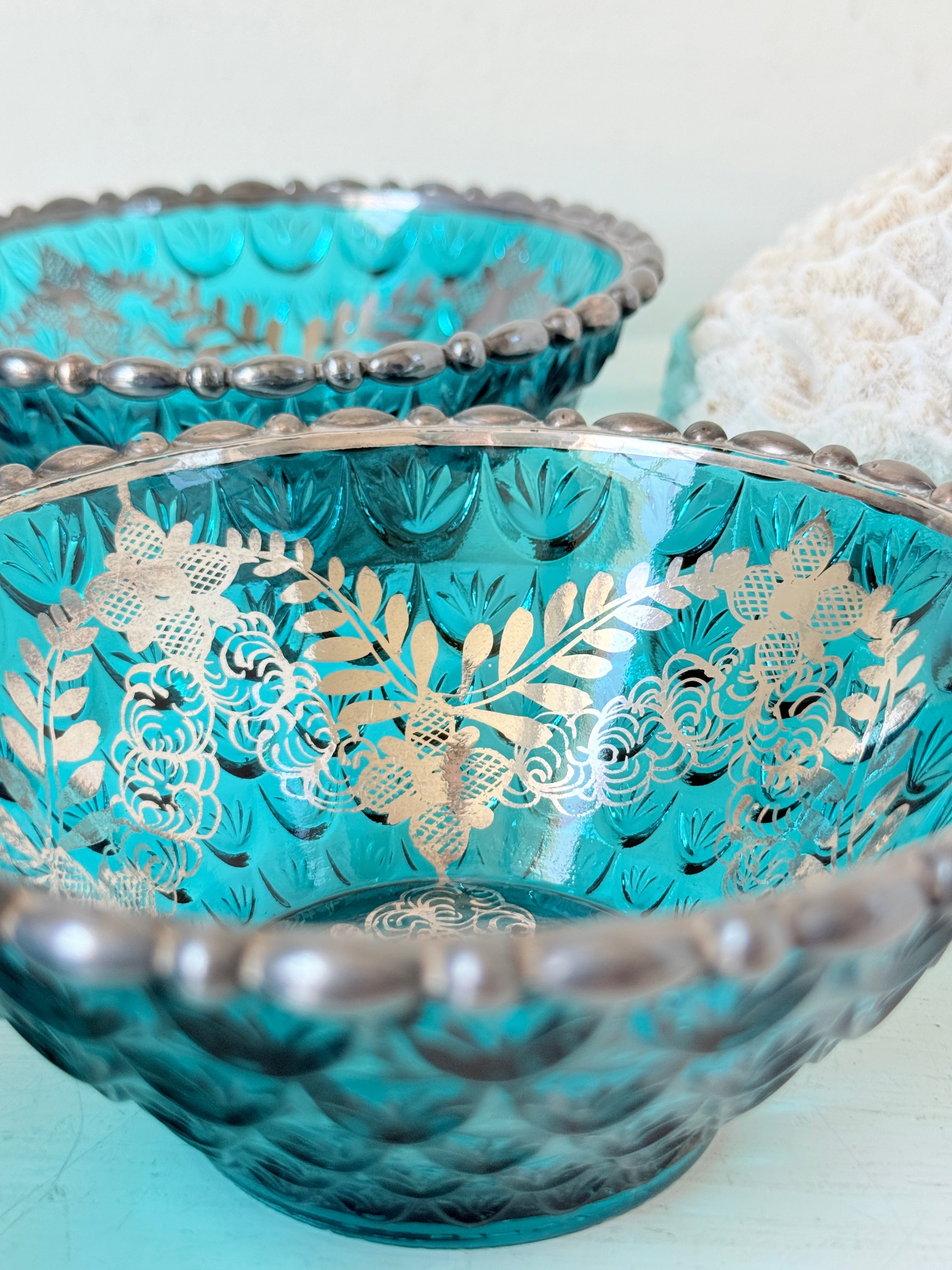 Set of four vintage teal pressed glass dessert bowls with gilt floral decoration, photographed on a white surface