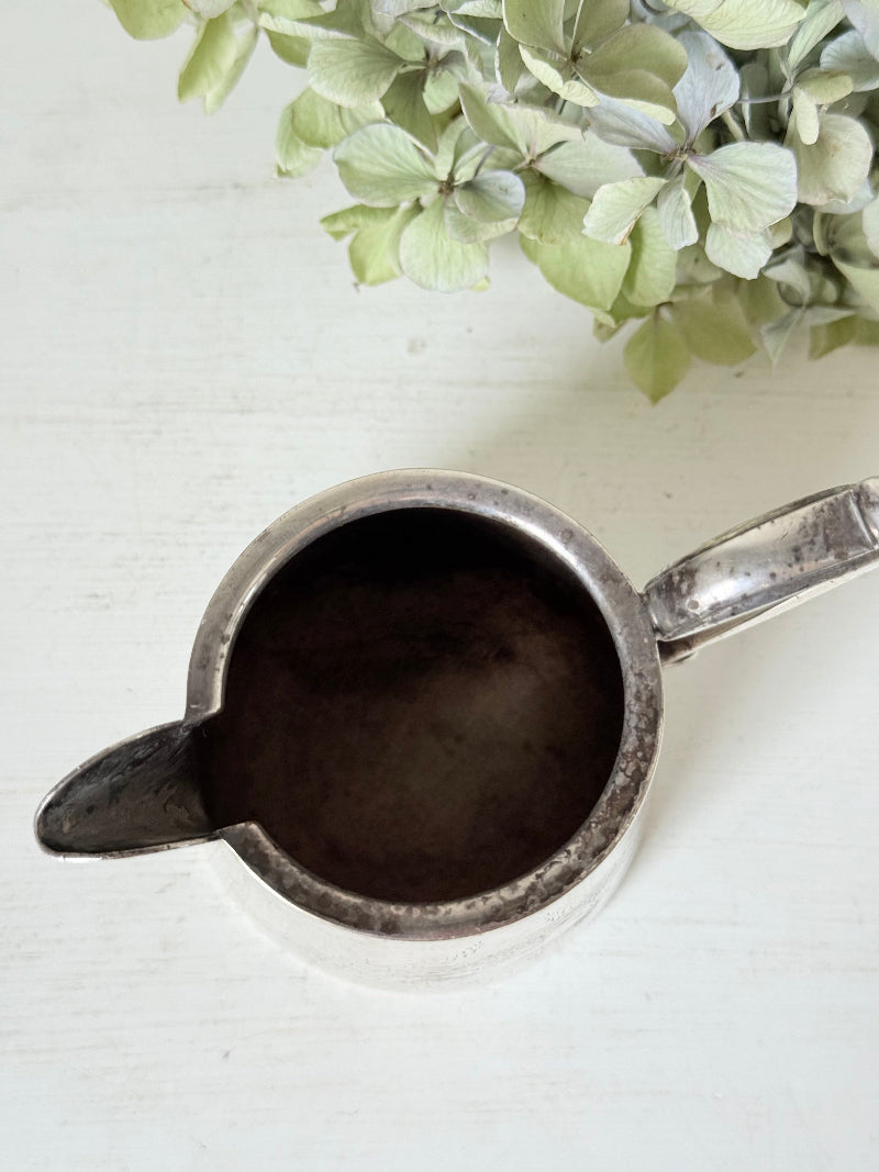 vintage silver plate jug with curved handle photographed on white surface with green hydrangeas
