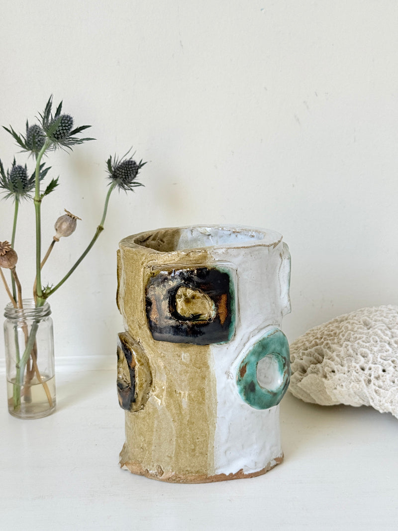 Vintage studio pottery vase in white, ochre and turquoise with abstract applied decoration, photographed on a white surface