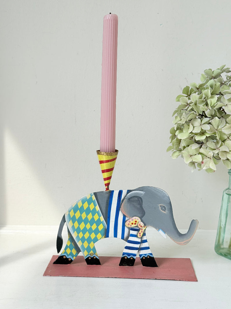 Hand painted metal elephant candlestick in circus-style decoration with colourful patterns, photographed on a white surface