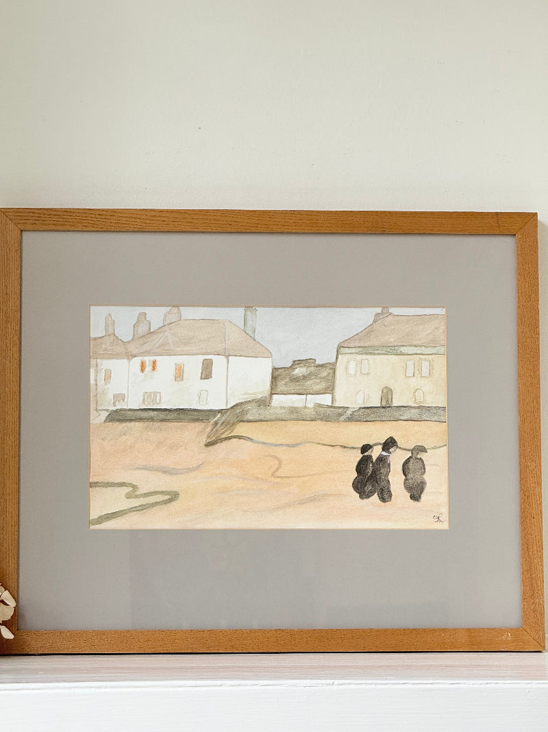 Framed neutral-toned village scene watercolour with figures in light oak-effect frame and pale grey mount, on white surface.