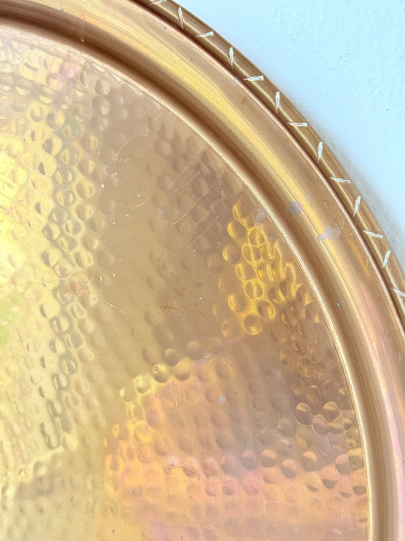 Lakeland Borrowdale hammered copper tray with warm patina, photographed on a white surface beside dried stems.