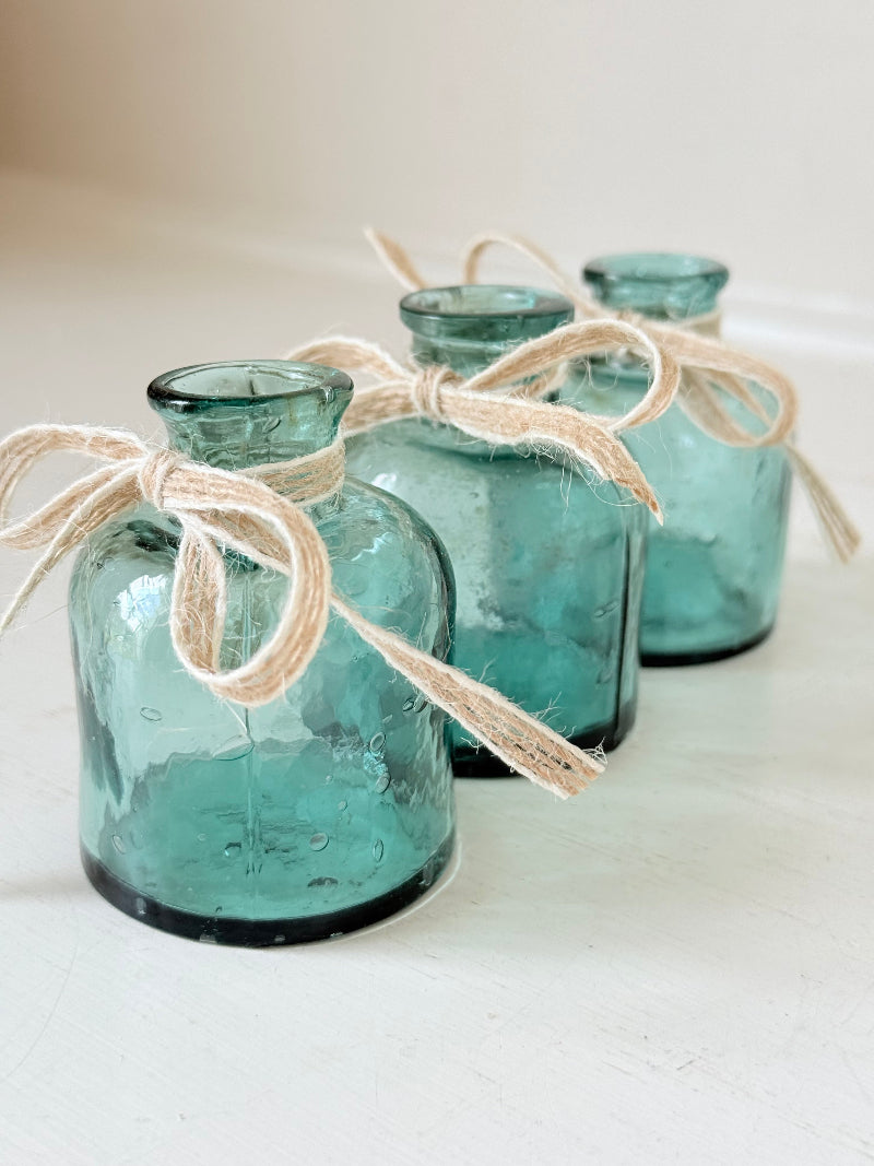 Set of antique green glass ink bottles with rounded forms, photographed on white surface.