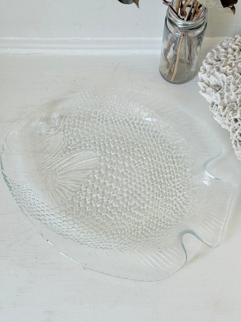 Vintage clear glass fish shaped serving dish with textured scale pattern photographed on a white surface