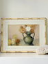 Vintage watercolour of chrysanthemums in green vase, under glass, in cream faux bamboo frame, photographed on white surface.