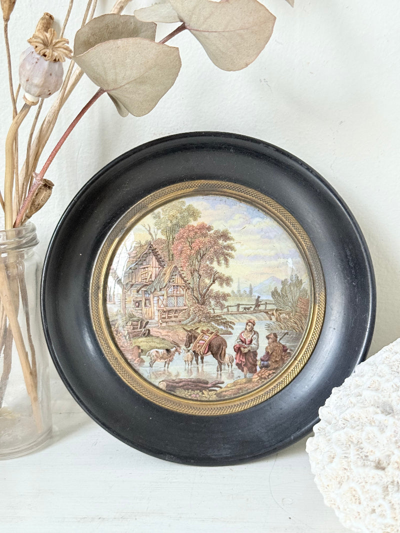 Antique Prattware framed pot lid with cottage scene photographed on a white surface.