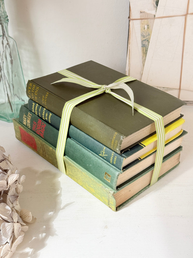 Bundle of vintage sage and olive green cloth books with red spine detail tied with a pale ribbon for styling