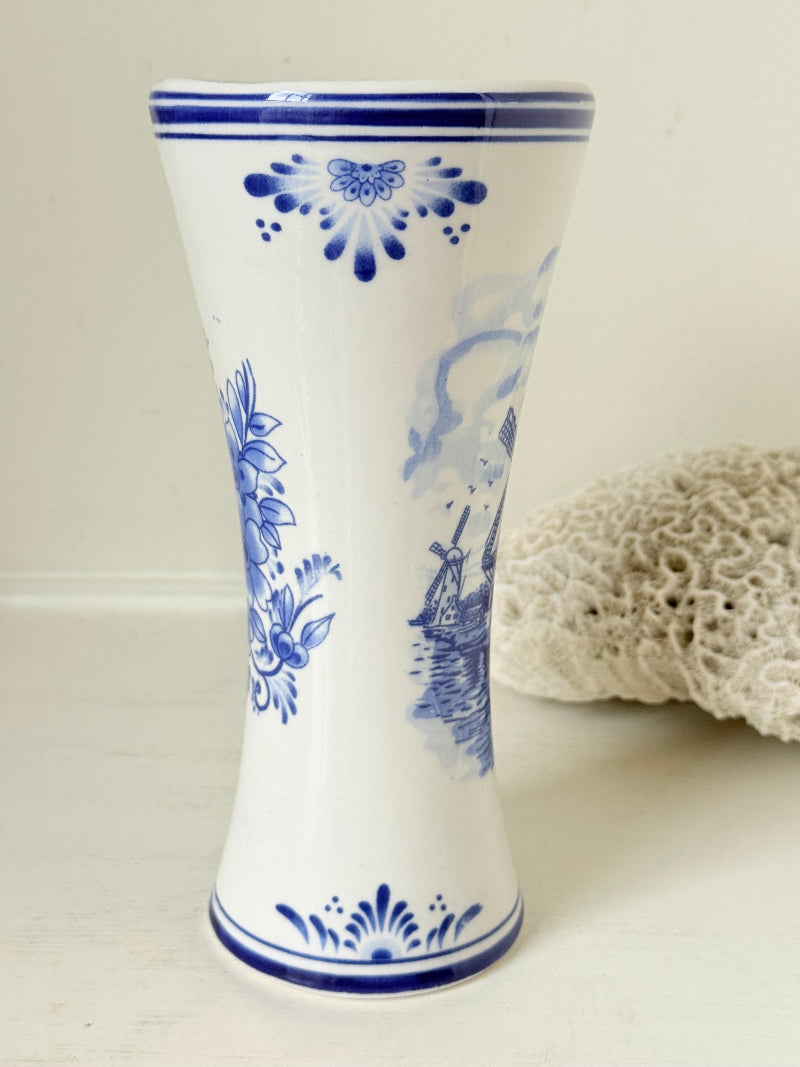 Blue and white Delft hand painted ceramic vase with windmill and floral decoration, photographed on white surface.