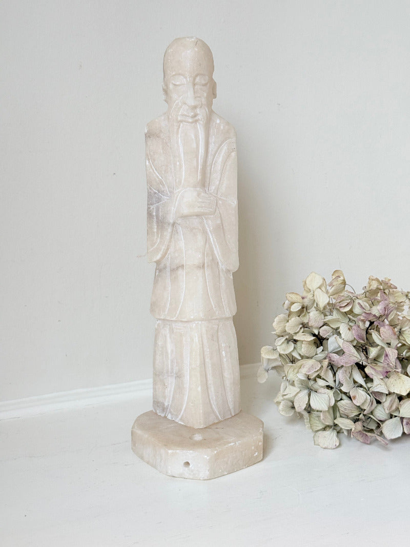 vintage alabaster gentleman figure on square base with carved detail, photographed on white surface with hydrangea flowers.