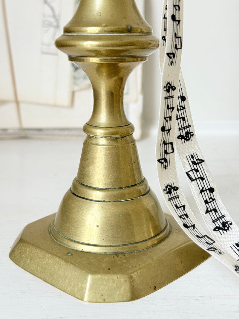 Pair of antique brass candlesticks with turned baluster stems and stepped bases holding coral tapers