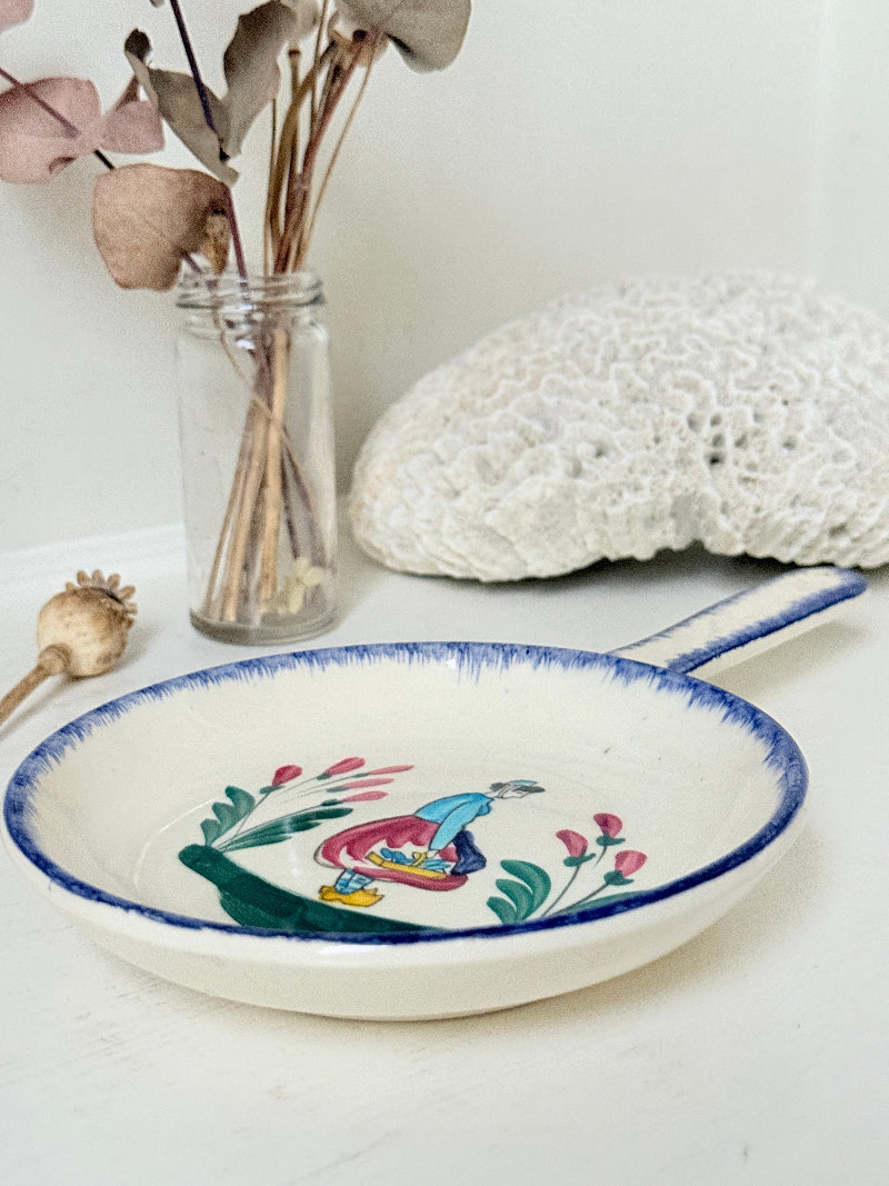 French Quimper faience handled wall dish with Petit Breton figure and blue rim, photographed on a white surface