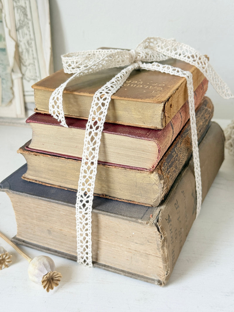 Antique decorative book bundle with faded hardback covers, aged pages and neutral lace tie for vintage interior styling