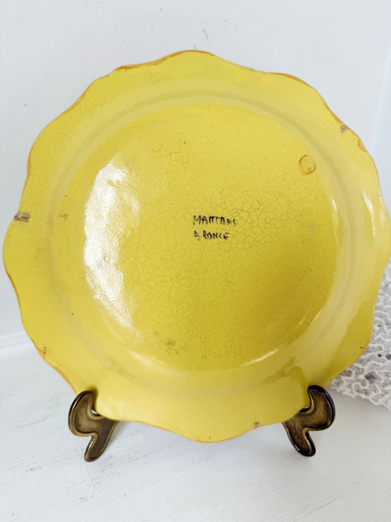 Vintage yellow French faïence plate with scalloped edge and blue floral decoration, photographed on a white surface