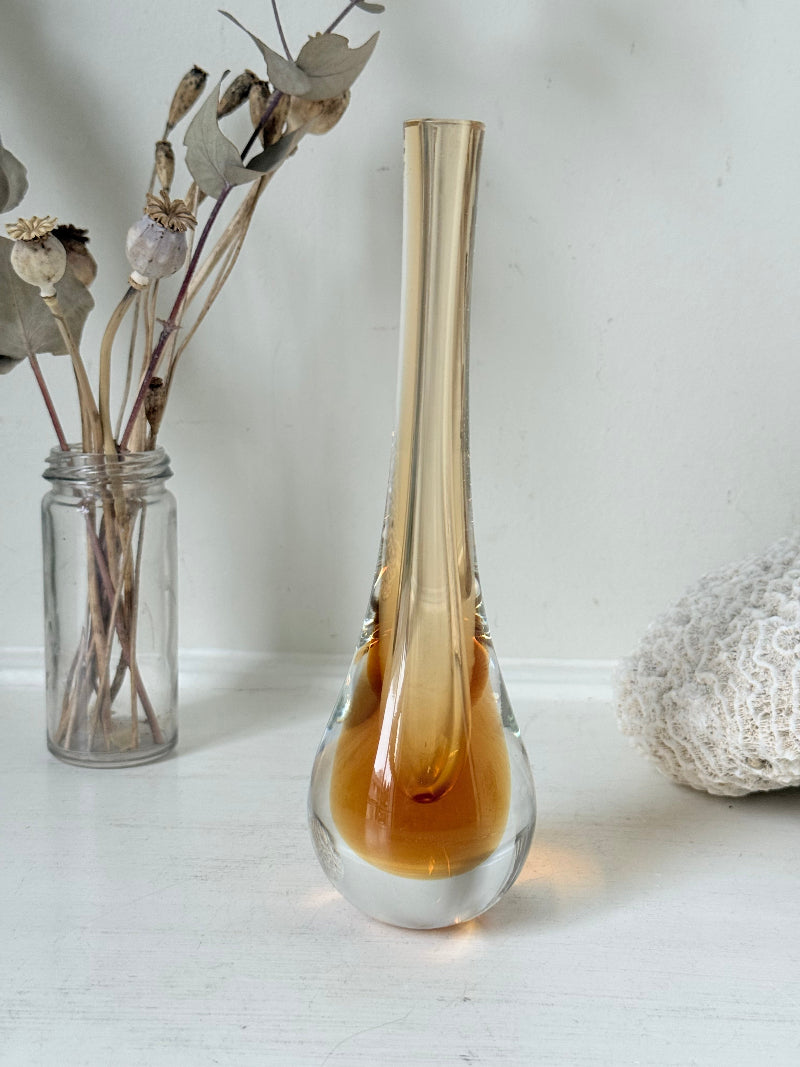 Amber and clear 1960s glass vase with narrow neck and rounded base, photographed on a white surface with dried stems.