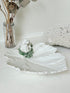 Italian ceramic dish featuring two white dogs on a sculpted leaf base, photographed on a white surface.