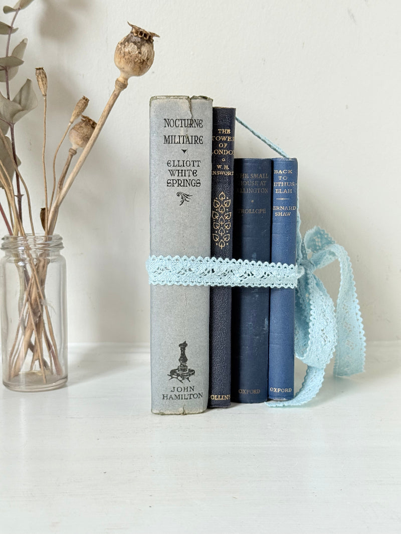 Vintage navy decorative book bundle tied with pale blue lace ribbon, photographed on a white surface