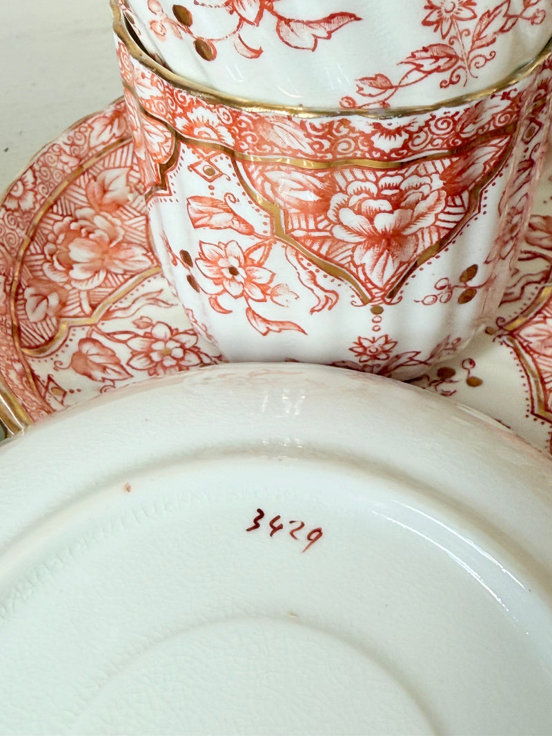 Vintage coral transferware coffee cans and saucers with scalloped edges and gold accents, set of ten, styled on a white surface.