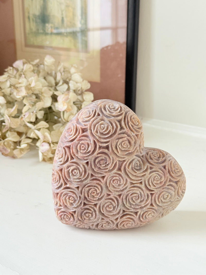 vintage pink stone heart with engraved roses and flat base on white surface