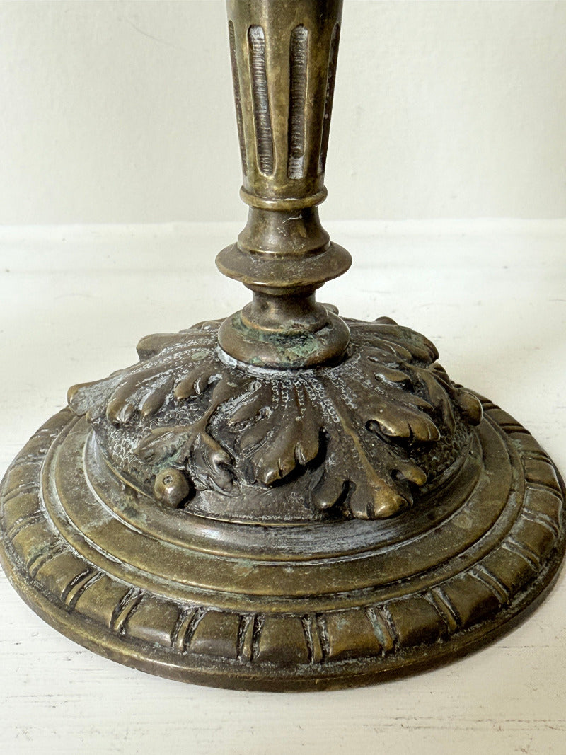 pair of antique brass candlesticks with turned detailing on white surface