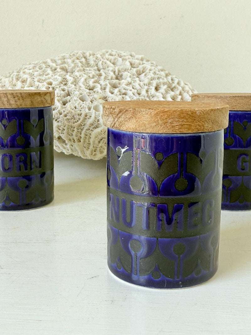 Set of three Hornsea Pottery spice jars in cobalt blue with wooden lids, labelled Ginger, Nutmeg, and Peppercorn, photographed on white surface