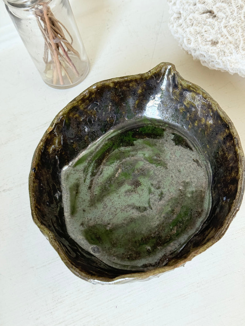 Studio pottery olive bowl with green and charcoal glaze, photographed on a white surface