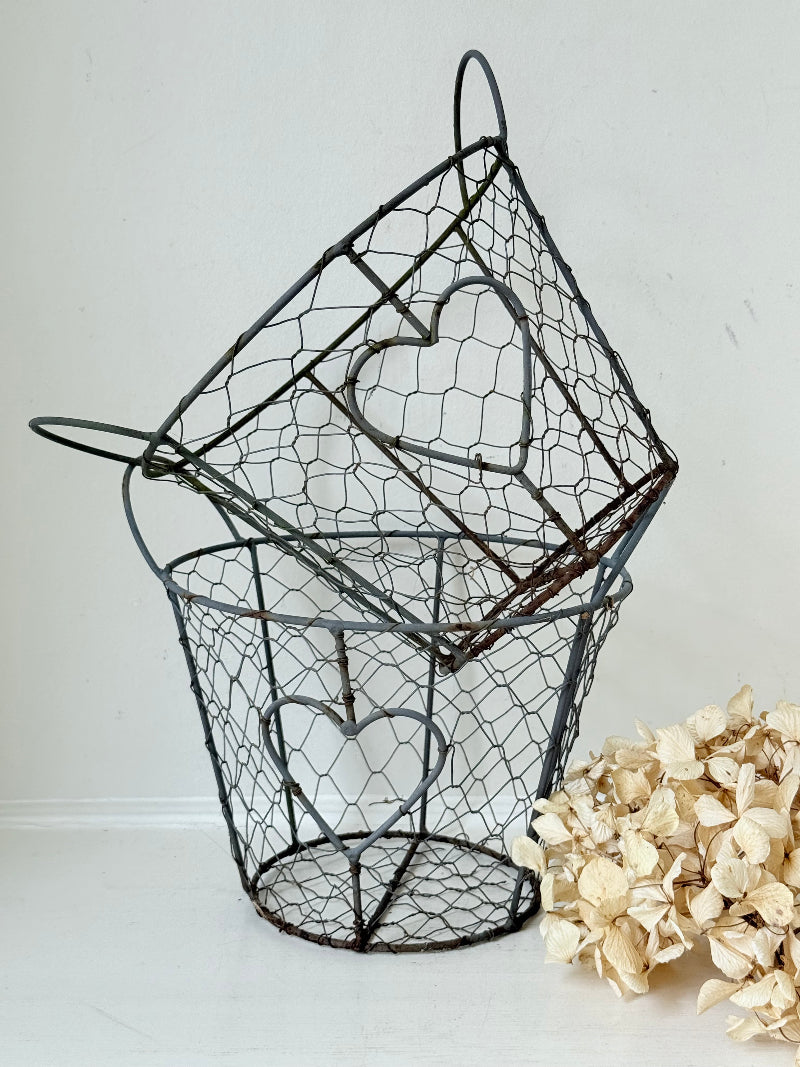 Pair of vintage decorative wire baskets with heart detail and aged patina photographed on a white surface