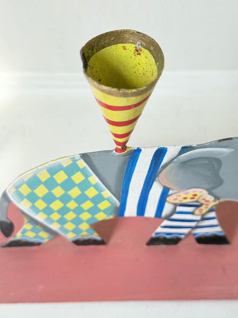 Hand painted metal elephant candlestick in circus-style decoration with colourful patterns, photographed on a white surface
