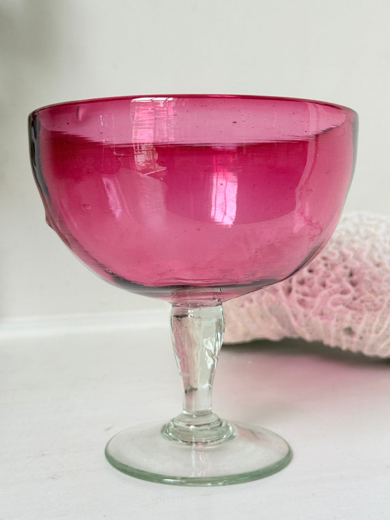Vintage cranberry glass bonbon dish with clear stem and foot, photographed on a white surface