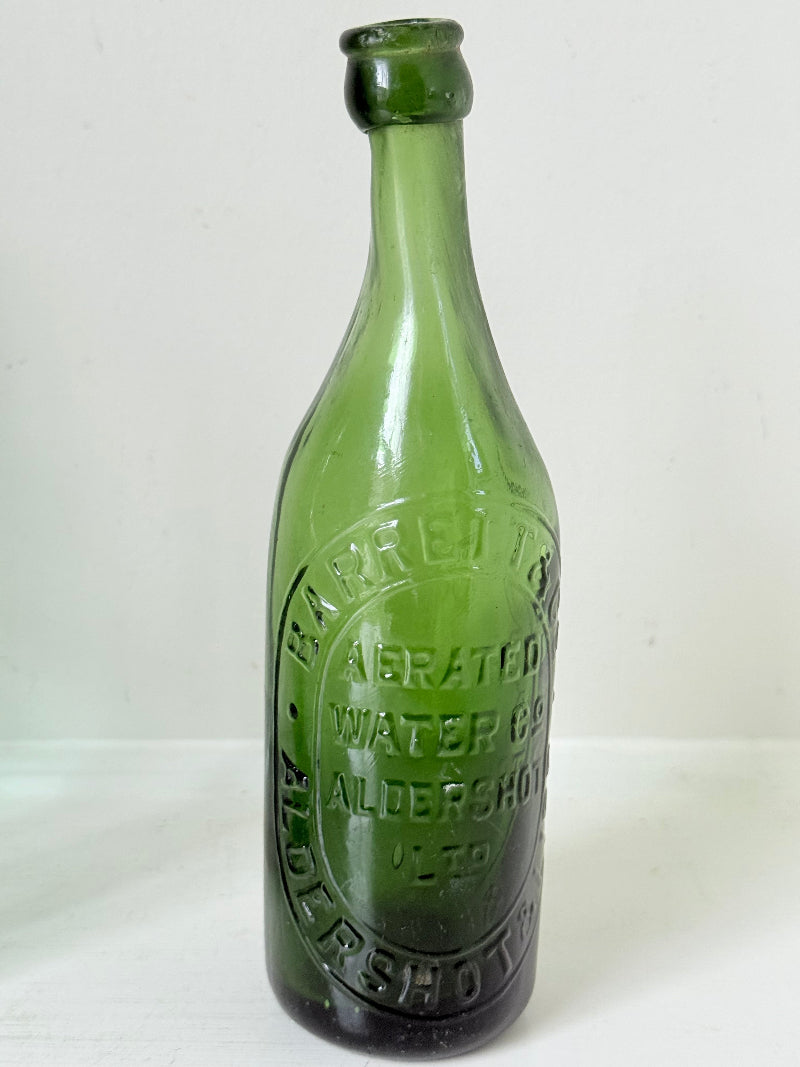 Trio of antique aqua and green glass bottles with embossed lettering, photographed on a white surface