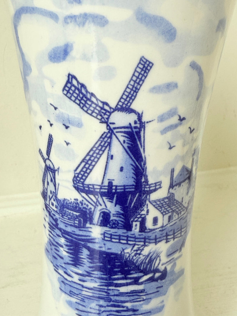 Blue and white Delft hand painted ceramic vase with windmill and floral decoration, photographed on white surface.