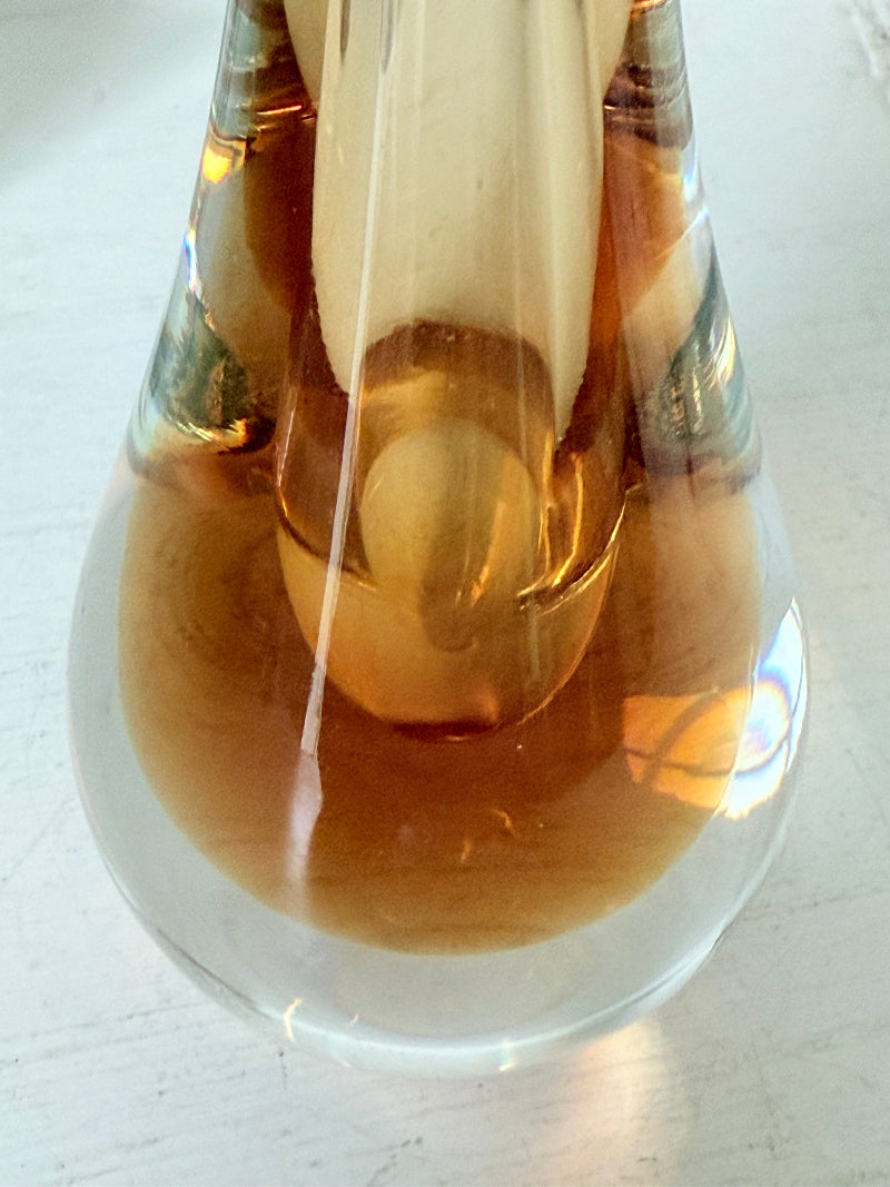 Amber and clear 1960s glass vase with narrow neck and rounded base, photographed on a white surface with dried stems.