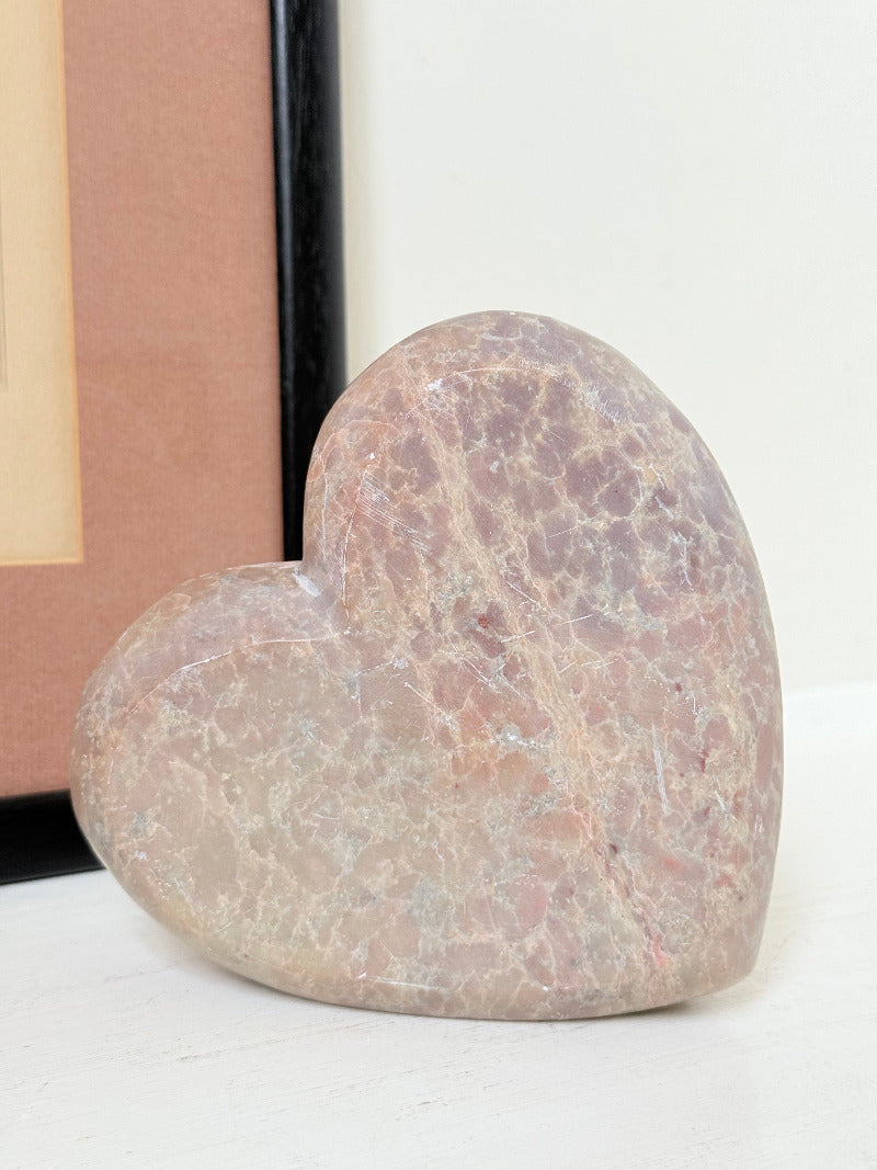 vintage pink stone heart with engraved roses and flat base on white surface