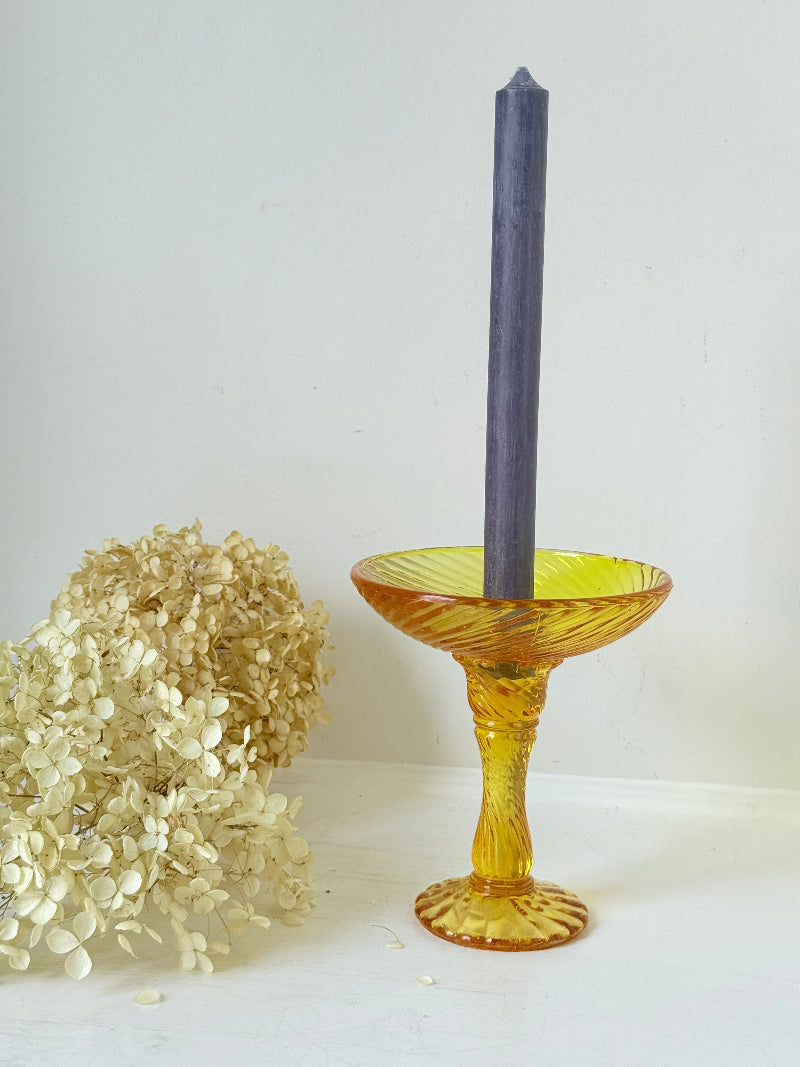 Amber pressed glass candle holder or compote with swirl design and pedestal base, photographed on a white background