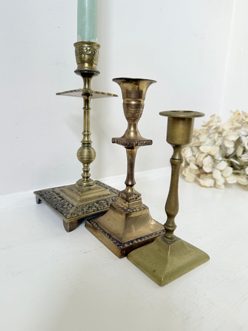 vintage brass trio of candlesticks in mixed designs photographed on white surface