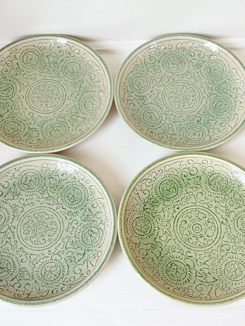 Set of four Thai stoneware plates with soft green celadon glaze on white surface