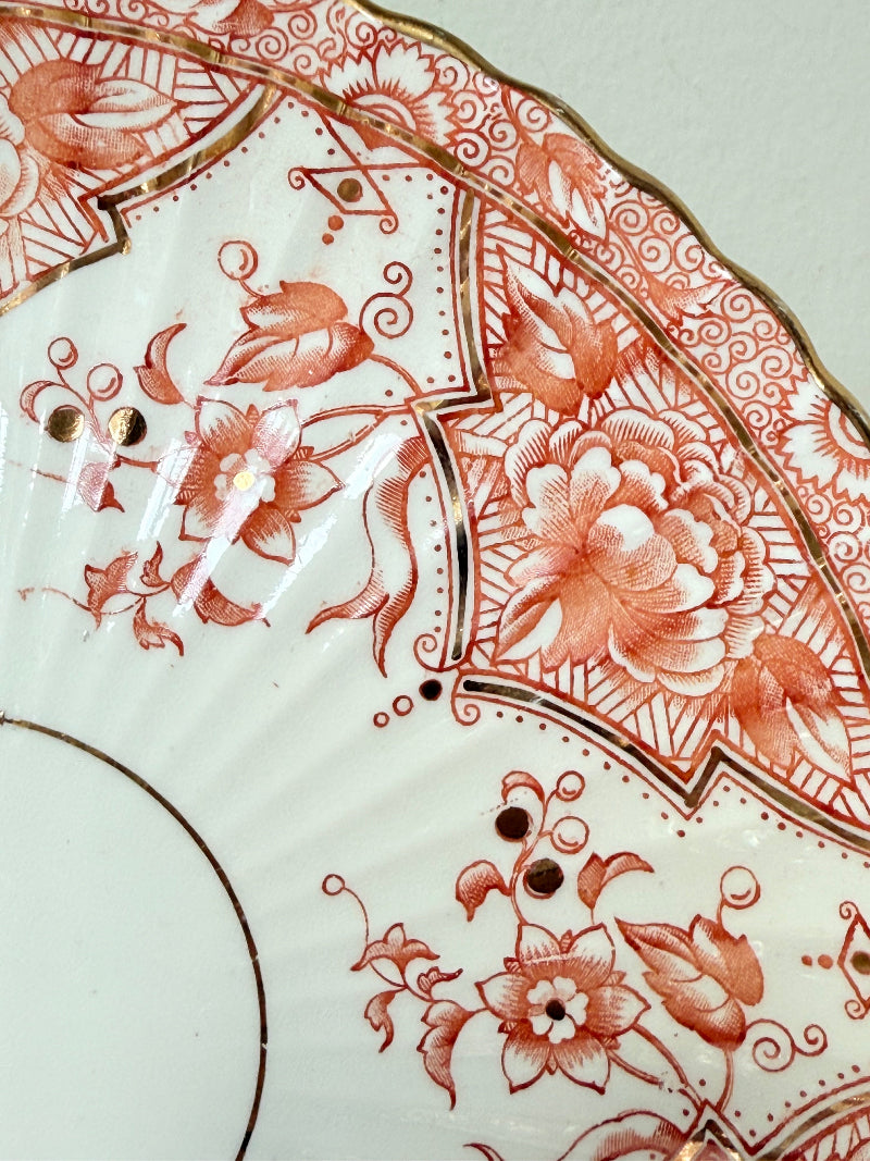 pair of vintage porcelain coral transfer plates with scalloped edges and gilt detail on white surface