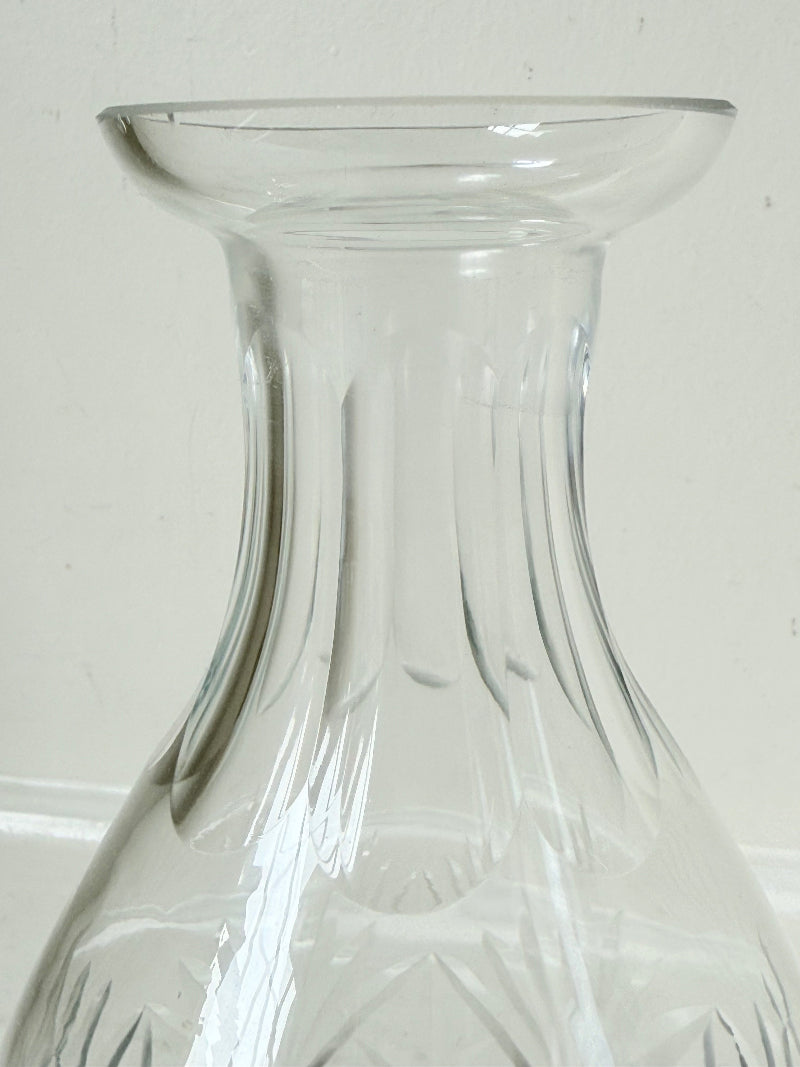 Vintage crystal decanter with faceted stopper and cut glass starburst design, photographed on a white surface
