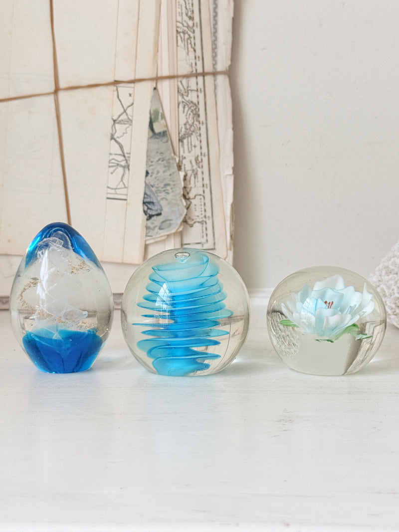 Trio of vintage turquoise blue glass paperweights with swirl, ribbed and floral detail in clear coloured glass