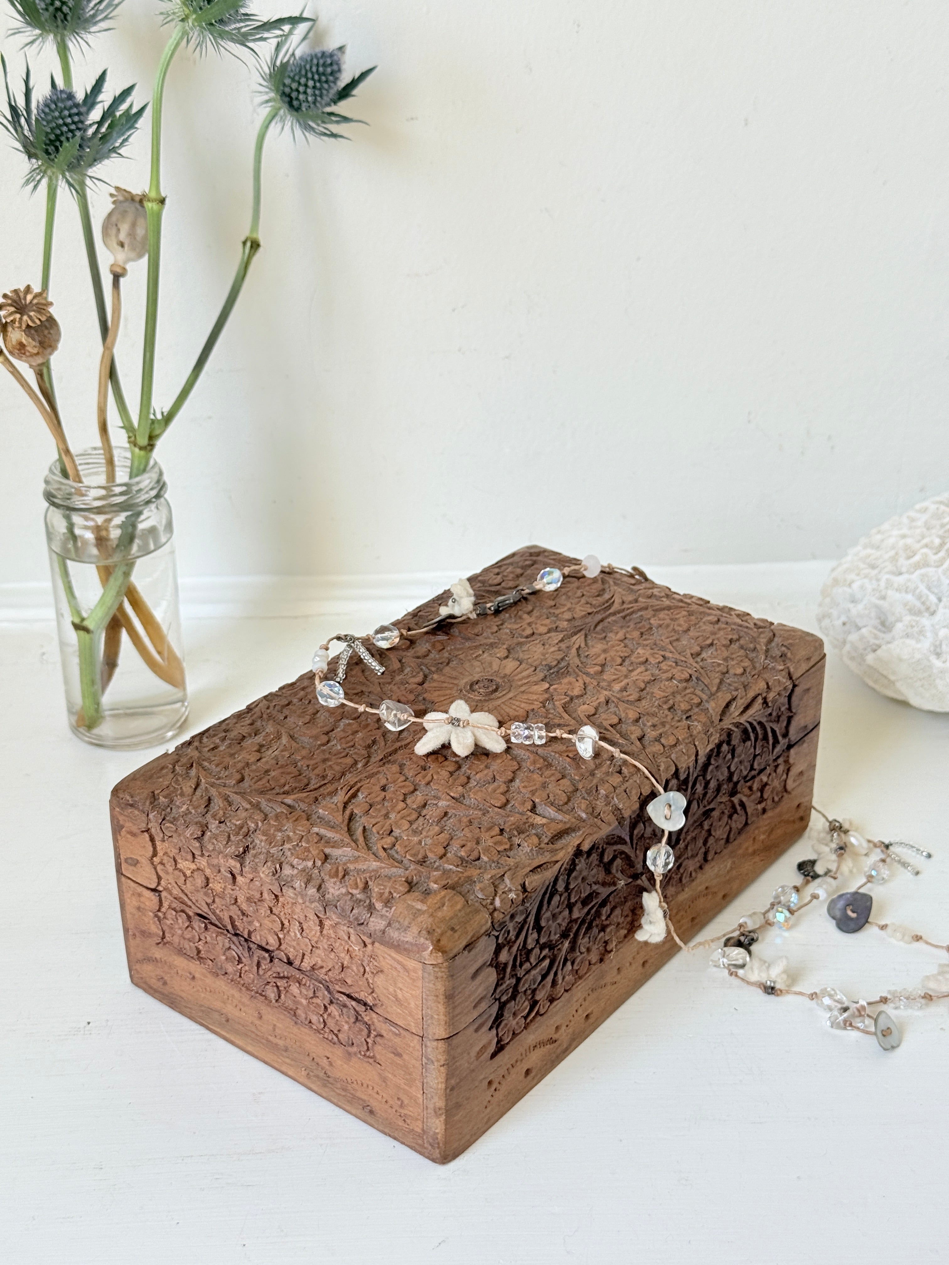 Vintage floral carved wooden jewellery box with detailed hand carved decoration, photographed on a white surface