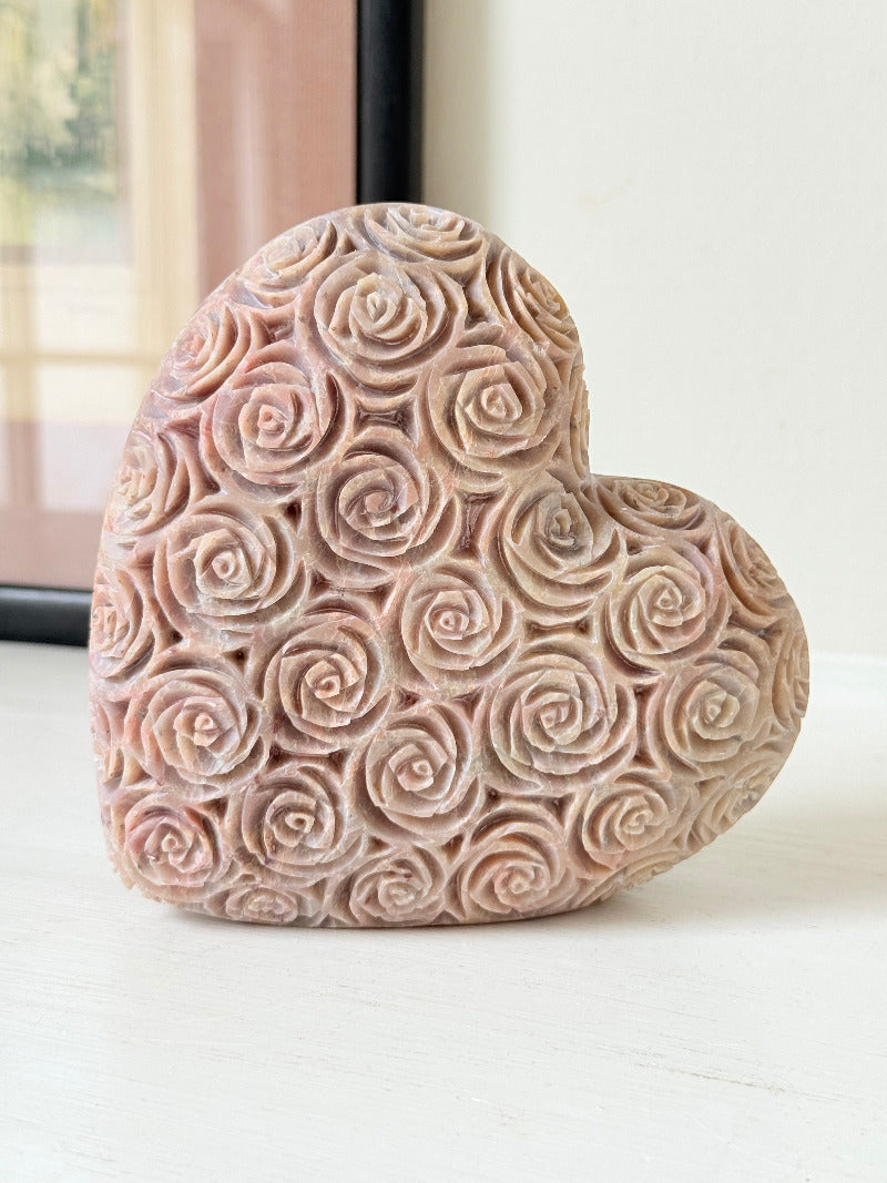 vintage pink stone heart with engraved roses and flat base on white surface