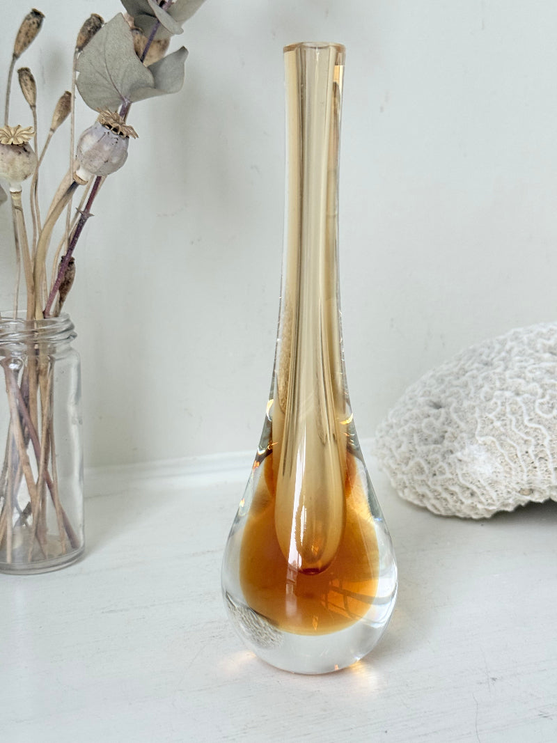 Amber and clear 1960s glass vase with narrow neck and rounded base, photographed on a white surface with dried stems.