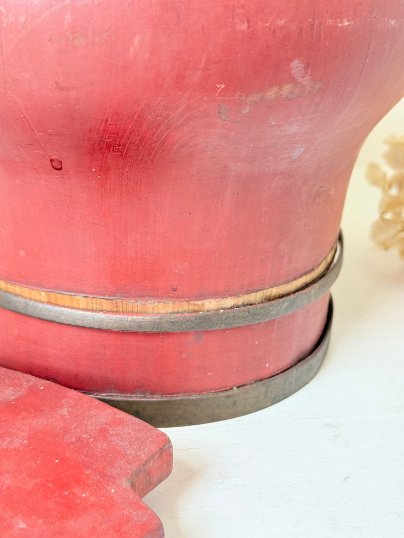 Vintage red painted wooden basket with upright handle and gold painted detail photographed on a white surface