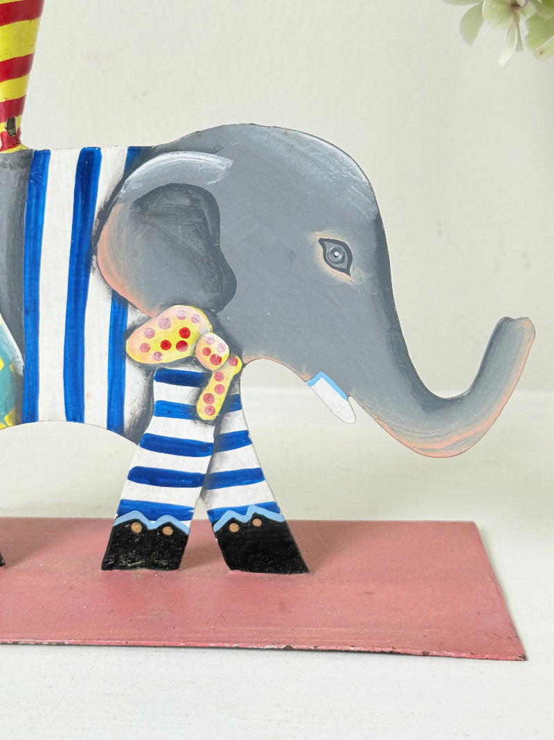 Hand painted metal elephant candlestick in circus-style decoration with colourful patterns, photographed on a white surface