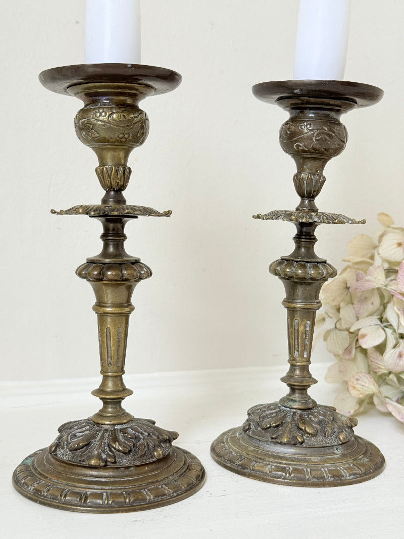 pair of antique brass candlesticks with turned detailing on white surface