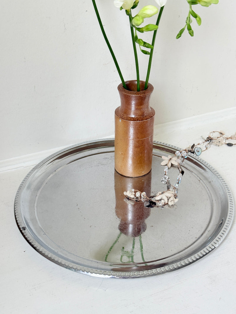 Vintage silver tone round tray with beaded edge, engraved surface detail and reflective finish for drinks or vanity styling