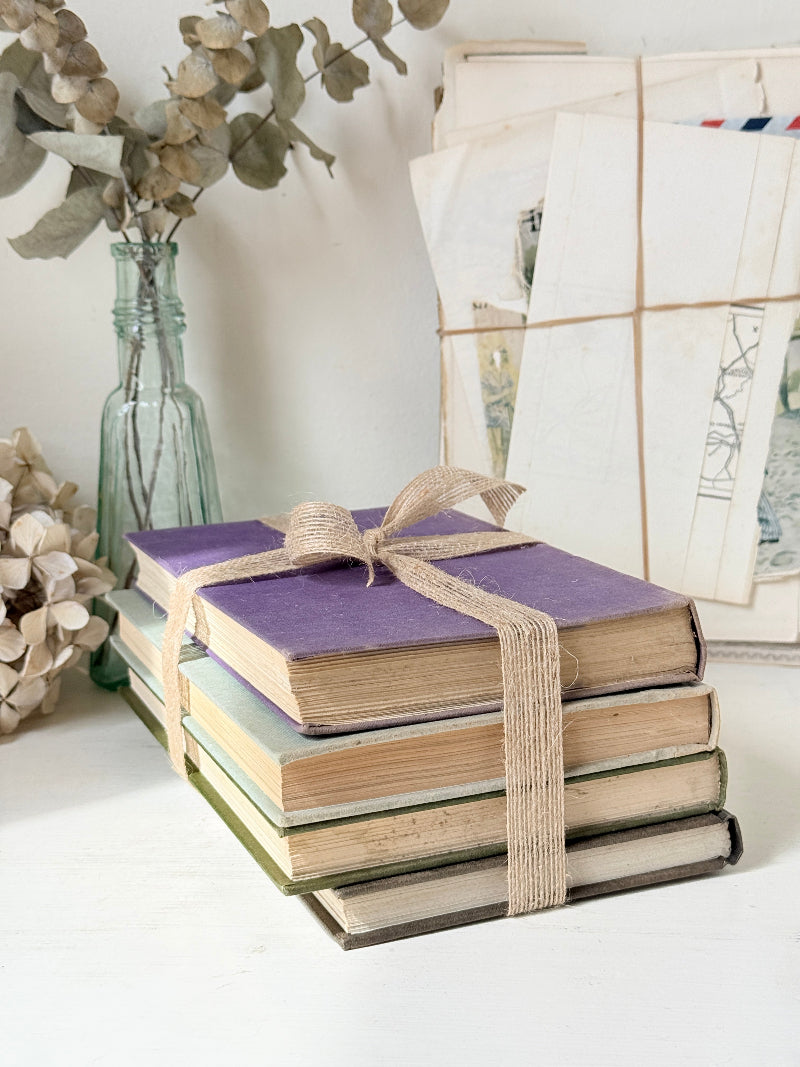 Bundle of vintage books with a heather purple cloth cover over green and cream spines tied with natural twine