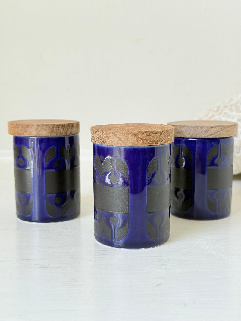 Set of three Hornsea Pottery spice jars in cobalt blue with wooden lids, labelled Ginger, Nutmeg, and Peppercorn, photographed on white surface