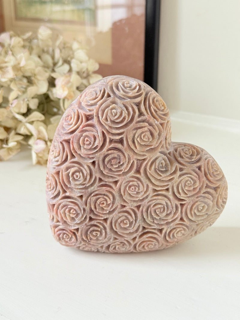 vintage pink stone heart with engraved roses and flat base on white surface