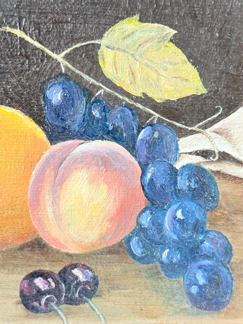 Still life oil painting of blue grapes, a peach, a partially visible orange, and two dark cherries on a wooden surface against a dark background.