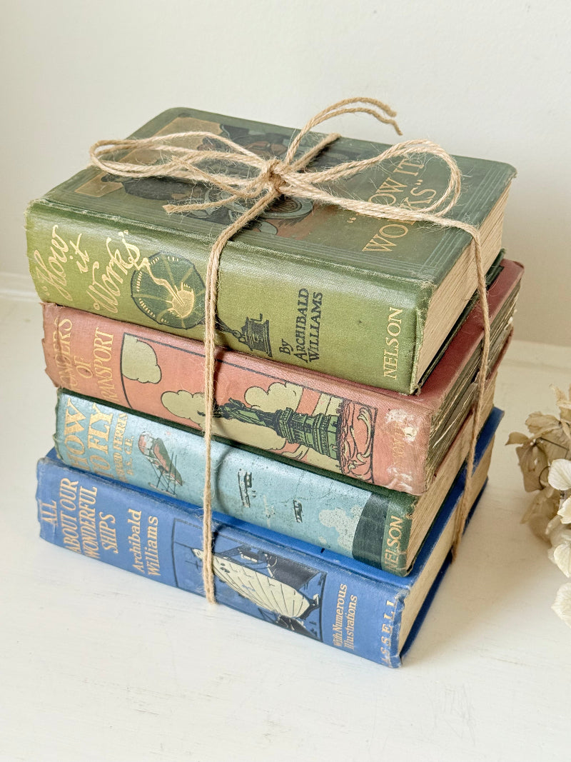 Vintage decorative book bundle in green, blue, and coral with printed lettering, tied with twine, photographed on a white surface